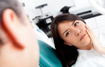 Woman with Pain Holding Her Jaw in Dentist Chair Kennesaw GA