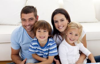 Portrat of happy family of four: parents with a little son and a daughter.