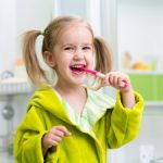 Cheerful little girl is brushing her teeth