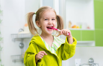 Cheerful little girl is brushing her teeth