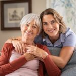 mature daughter with older mother embrace on the sofa